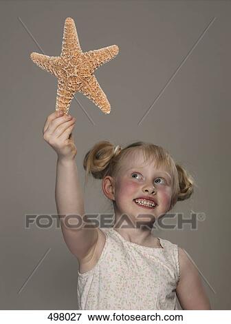 Stock Photo - A young girl holding up a starfish. Fotosearch
