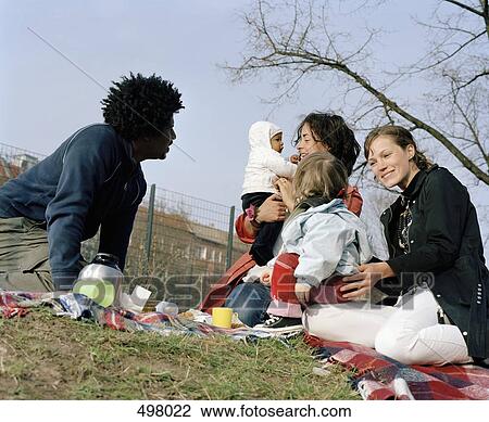 Friends and family having a picnic in a park View Large Photo Image Stock Image - Friends and family having a picnic in a park. Fotosearch