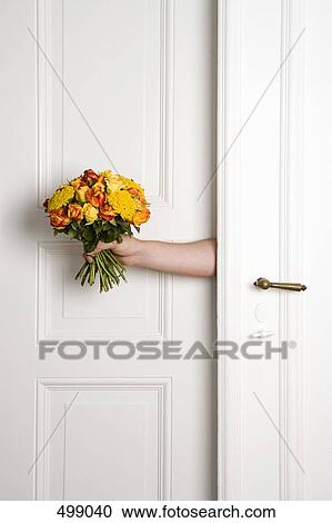 A man holding a bunch of flowers inside a door View Large Photo Image Stock Image - A man holding a bunch of flowers inside a door. Fotosearch