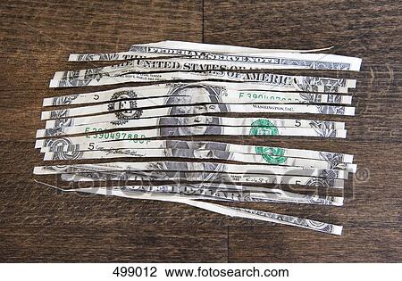 Stock Image - A shredded one dollar note on a wooden table. Fotosearch