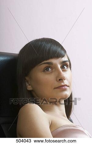 A young woman leaning in a chair and looking away View Large Photo Image Stock Image - A young woman leaning in a chair and looking away. Fotosearch