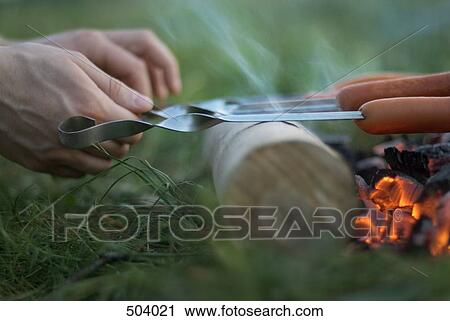 Detail of a man grilling sausages over a fire View Large Photo Image Stock Image - Detail of a man grilling sausages over a fire. Fotosearch