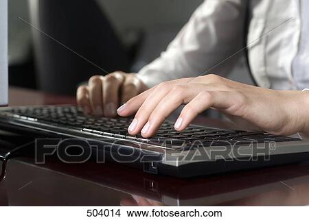 Detail of a woman using a computer at a desk View Large Photo Image Picture - Detail of a woman using a computer at a desk. Fotosearch