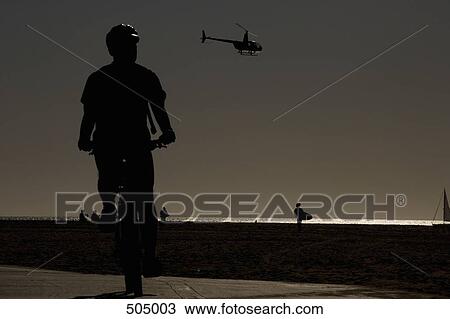 A helicopter flying above a beach at sunset View Large Photo Image Stock Image - A helicopter flying above a beach at sunset. Fotosearch