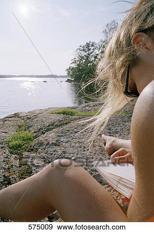 Stock Photo - A young woman reading by a lake. Fotosearch