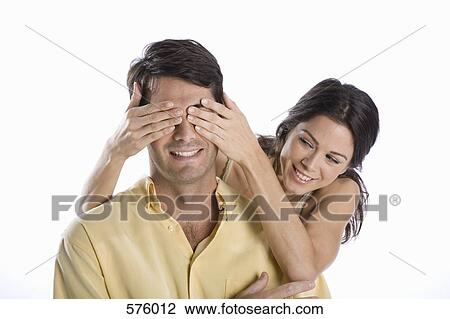 Stock Image - A woman covering a man's eyes. Fotosearch