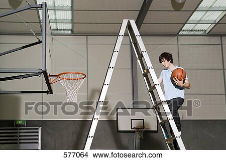 A man climbing up a ladder next to a basketball hoop View Large Photo Image Picture - A man climbing up a ladder next to a basketball hoop. Fotosearch