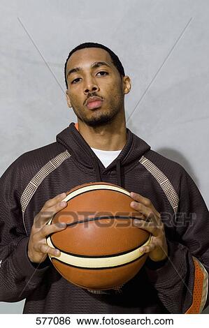 Stock Photograph - A young man holding a basketball in both hands. Fotosearch