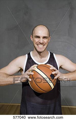 Stock Image - A young man holding a basketball preparing to throw it. Fotosearch