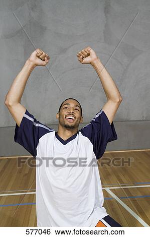 Stock Photograph - A young man kneeling with his arms raised in victory. Fotosearch
