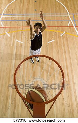 A young man shooting a basketball into a basketball hoop View Large Photo Image Stock Image - A young man shooting a basketball into a basketball hoop. Fotosearch