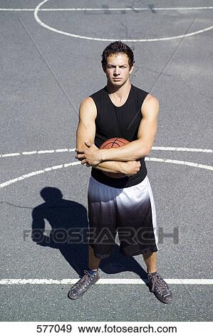 Stock Photo - A young man standing on the free throw line at an outdoor basketball court. Fotosearch