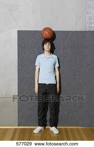 Stock Photo - A young man standing with a basketball balanced on his head. Fotosearch