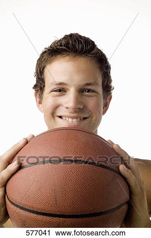 Stock Image - Studio portrait of a young man holding a basketball. Fotosearch