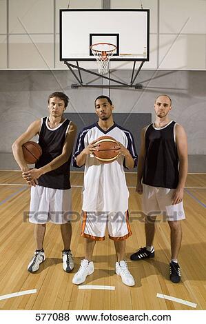 Stock Photo - Three basketball players standing on a basketball court. Fotosearch