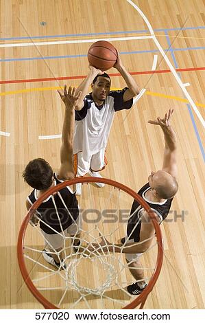 Stock Image - Three young men playing basketball. Fotosearch