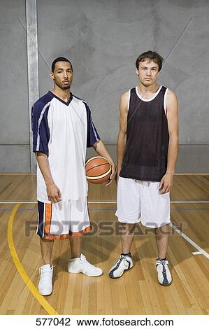 Stock Image - Two Young Men standing on a basketball court. Fotosearch