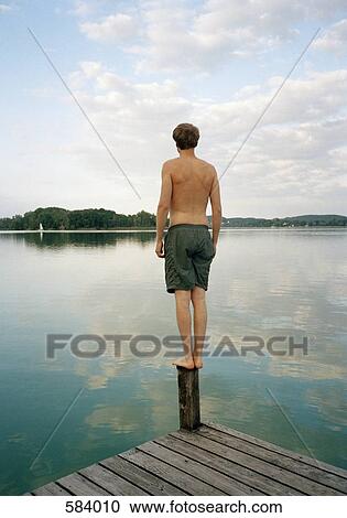 A man standing on a jetty on a lake View Large Photo Image Stock Image - A man standing on a jetty on a lake. Fotosearch