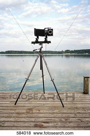 An old fashioned camera on a tripod in front of a lake View Large Photo Image Stock Photo - An old fashioned camera on a tripod in front of a lake. Fotosearch