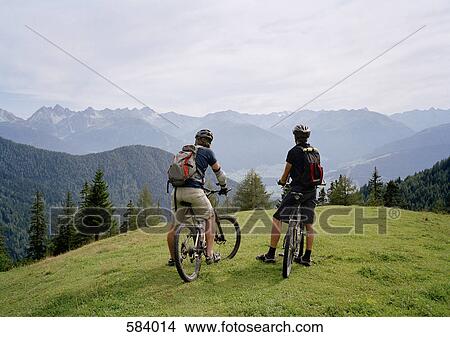 Picture - Two cyclists on the top of a hill looking at the view. Fotosearch