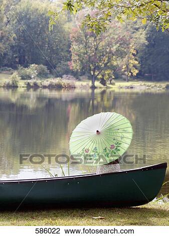 A portrait of an unrecognizable person holding a paper umbrella in a moored boat View Large Photo Image Stock Image - A portrait of an unrecognizable person holding a paper umbrella in a moored boat. Fotosearch