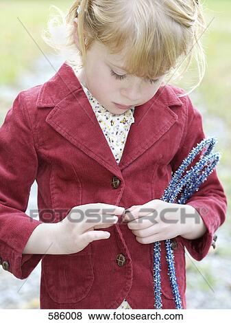 Stock Photo - A young girl buttoning her coat. Fotosearch