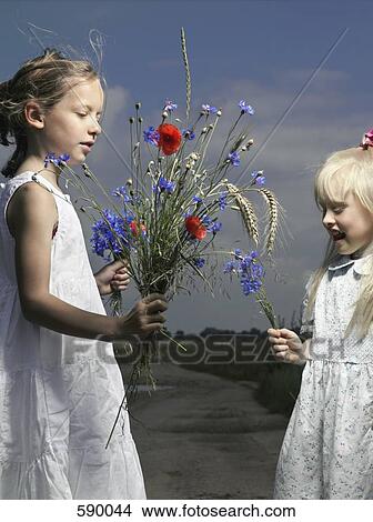 Two girls holding bunches on wildflowers View Large Photo Image Picture - Two girls holding bunches on wildflowers. Fotosearch