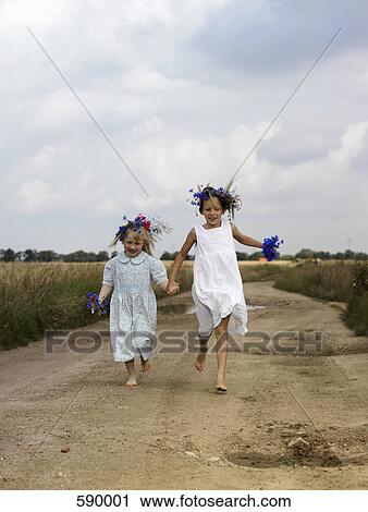 Two young girls running along a country road View Large Photo Image Stock Image - Two young girls running along a country road. Fotosearch