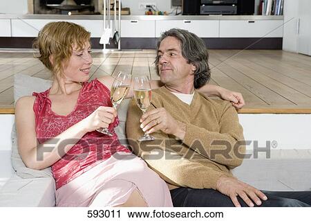 A couple sitting on a sofa and toasting with champagne View Large Photo Image Stock Image - A couple sitting on a sofa and toasting with champagne. Fotosearch