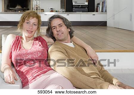 Picture - A couple sitting on the sofa together. Fotosearch