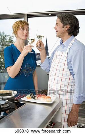Stock Photo - A couple toasting in the kitchen. Fotosearch