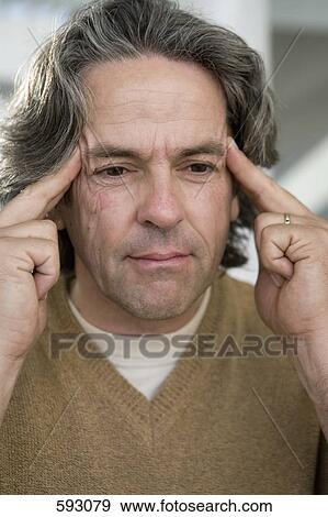 Stock Photo - A man rubbing his temples. Fotosearch