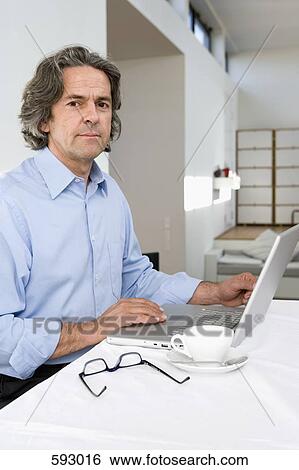 Stock Photograph - A man using a laptop computer at home. Fotosearch