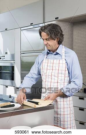 A mature man preparing sushi in the kitchen View Large Photo Image Stock Image - A mature man preparing sushi in the kitchen. Fotosearch