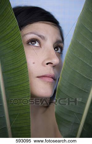 Stock Photography - A woman behind banana leaves. Fotosearch