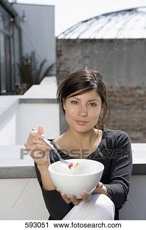 A woman eating breakfast on a roof terrace View Large Photo Image Stock Image - A woman eating breakfast on a roof terrace. Fotosearch