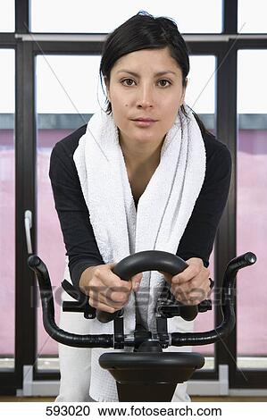 A woman on an exercise bike View Large Photo Image Stock Image - A woman on an exercise bike. Fotosearch