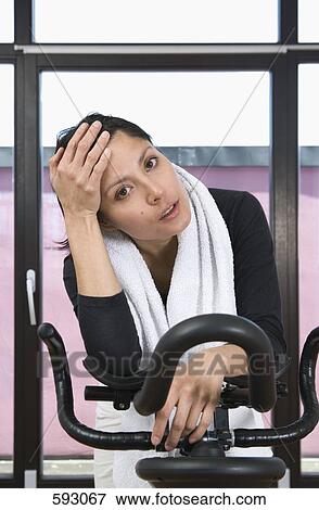 A woman on an exercise bike View Large Photo Image Stock Photo - A woman on an exercise bike. Fotosearch