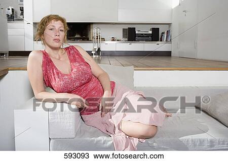 Stock Image - A woman sitting on a sofa. Fotosearch