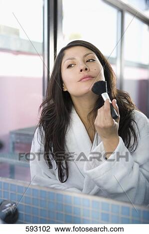 Stock Image - A young woman applying face powder with a make-up brush. Fotosearch