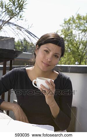 A young woman drinking coffee on a rooftop garden View Large Photo Image Stock Photography - A young woman drinking coffee on a rooftop garden. Fotosearch