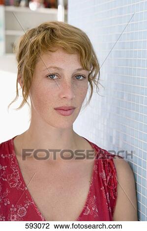Stock Image - Portrait of a woman leaning against a tiled wall. Fotosearch