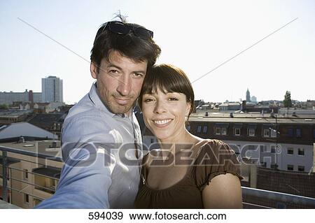 Stock Photo - A couple photographing themselves on a rooftop terrace. Fotosearch