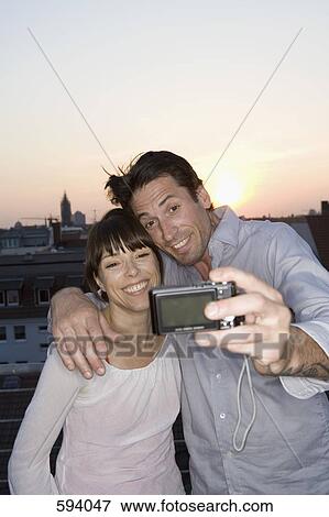 A couple photographing themselves on a rooftop terrace View Large Photo Image Stock Photo - A couple photographing themselves on a rooftop terrace. Fotosearch