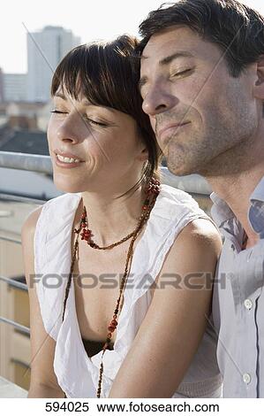 A couple sitting with their eyes closed on a rooftop terrace View Large Photo Image Stock Photography - A couple sitting with their eyes closed on a rooftop terrace. Fotosearch