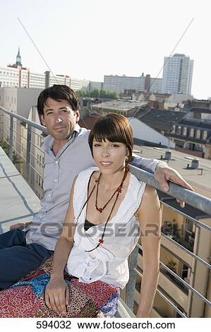 A man and a woman sitting together on a rooftop terrace View Large Photo Image Stock Image - A man and a woman sitting together on a rooftop terrace. Fotosearch