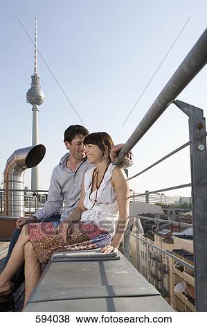 A man and a woman sitting together on a rooftop terrace View Large Photo Image Stock Photo - A man and a woman sitting together on a rooftop terrace. Fotosearch