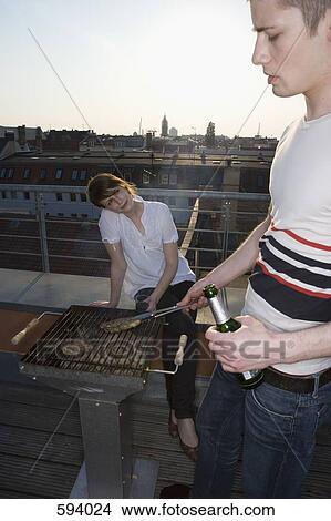 A young couple having a barbeque on a rooftop terrace View Large Photo Image Picture - A young couple having a barbeque on a rooftop terrace. Fotosearch