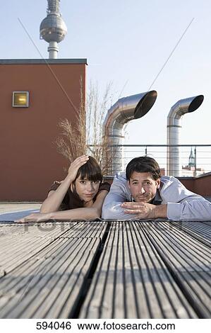 Portrait of a man and a woman lying together on a rooftop terrace View Large Photo Image Stock Photograph - Portrait of a man and a woman lying together on a rooftop terrace. Fotosearch