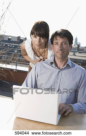 Two people using a laptop on a terrace View Large Photo Image Picture - Two people using a laptop on a terrace. Fotosearch